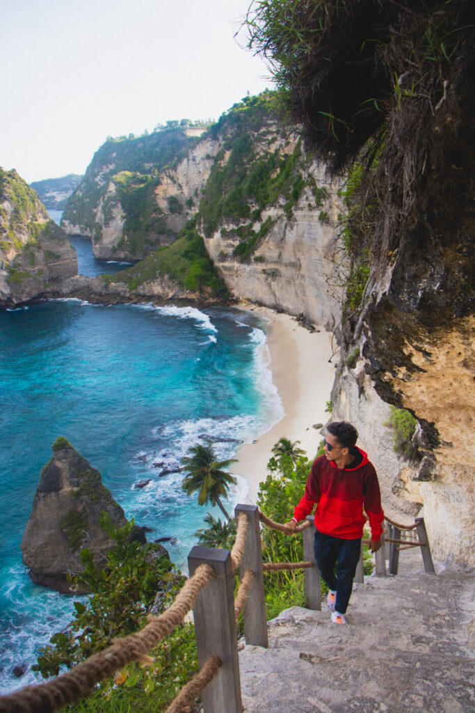 Traveler walking down the cliffside stairs at Diamond Beach, Bali
