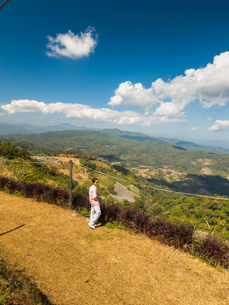 Traveler standing at the edge of Ban Mai Viewpoint looking out over the mountains on the Samoeng Loop.