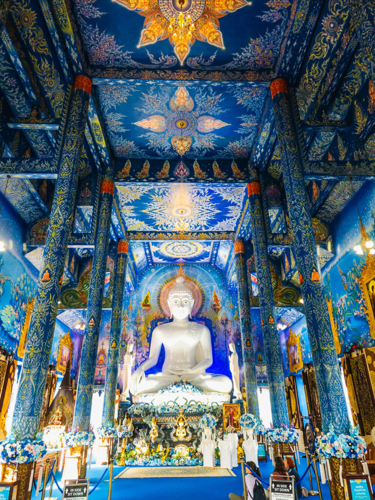 Blue Temple Chiang Rai interior with large white Buddha statue and gold details