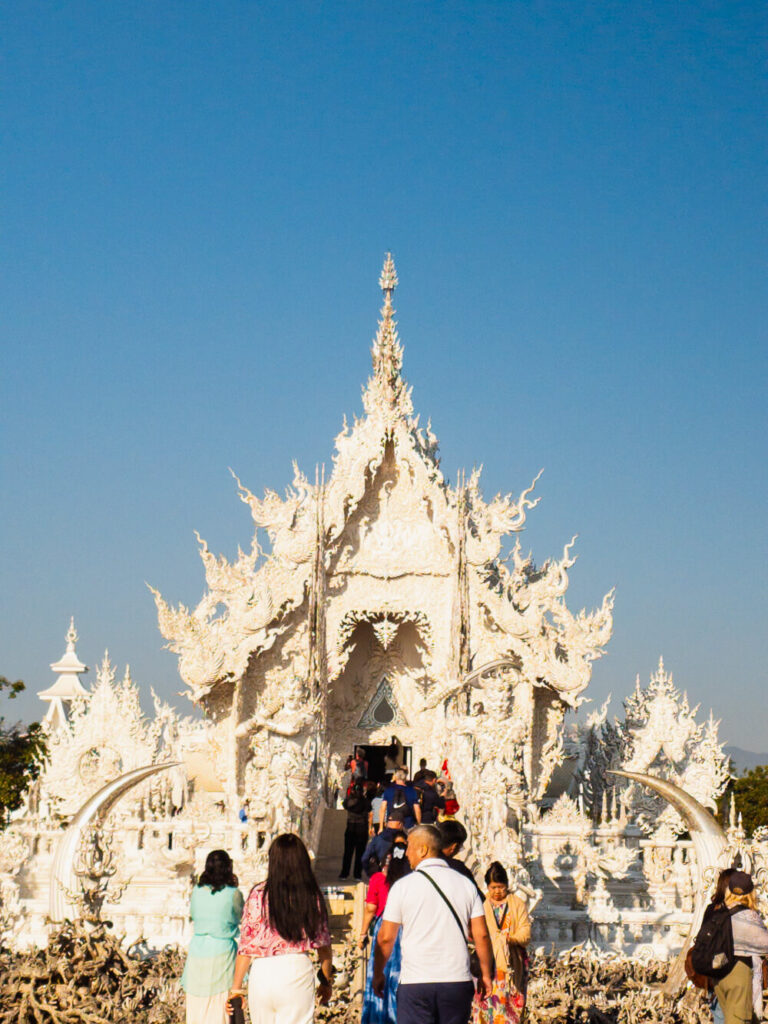 Crowded White Temple Chiang Rai during midday with tourists taking photos