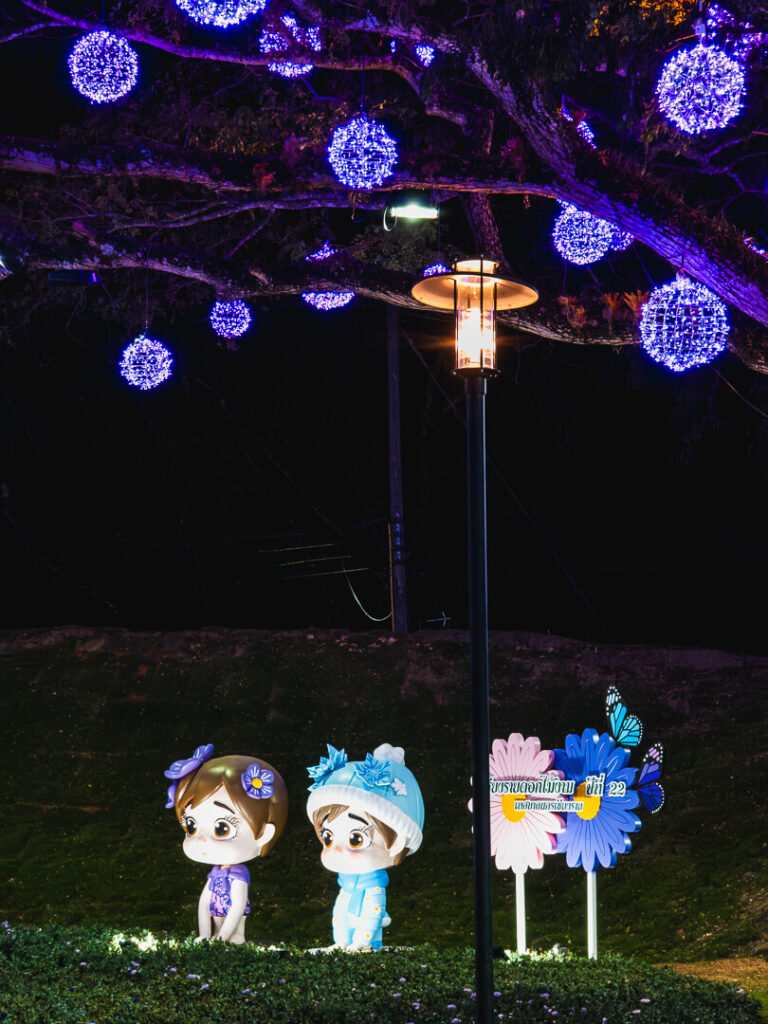 Two colorful traditional-style doll statues standing near the entrance of the flower garden.