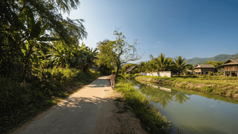 A traveler walking near a peaceful, hidden riverside cafe while riding the Samoeng Loop Chiang Mai motorbike route.
