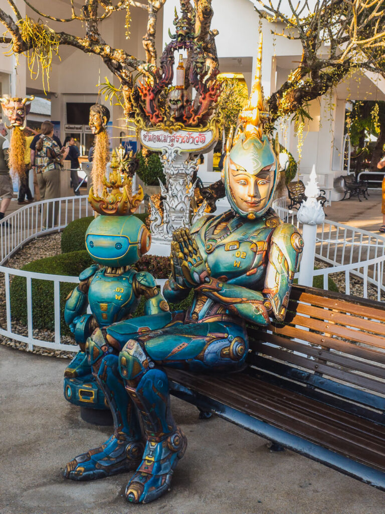 Iron Man statue sitting on bench outside White Temple Wat Rong Khun