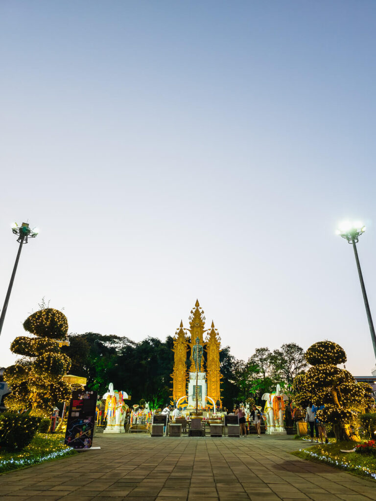 The King Menrai Monument in Chiang Rai city center illuminated at night with golden statues.