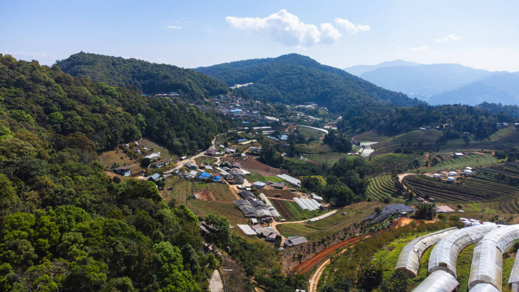 High-angle drone shot showing the winding mountain roads and lush green valleys of the Samoeng Loop Chiang Mai, Thailand.