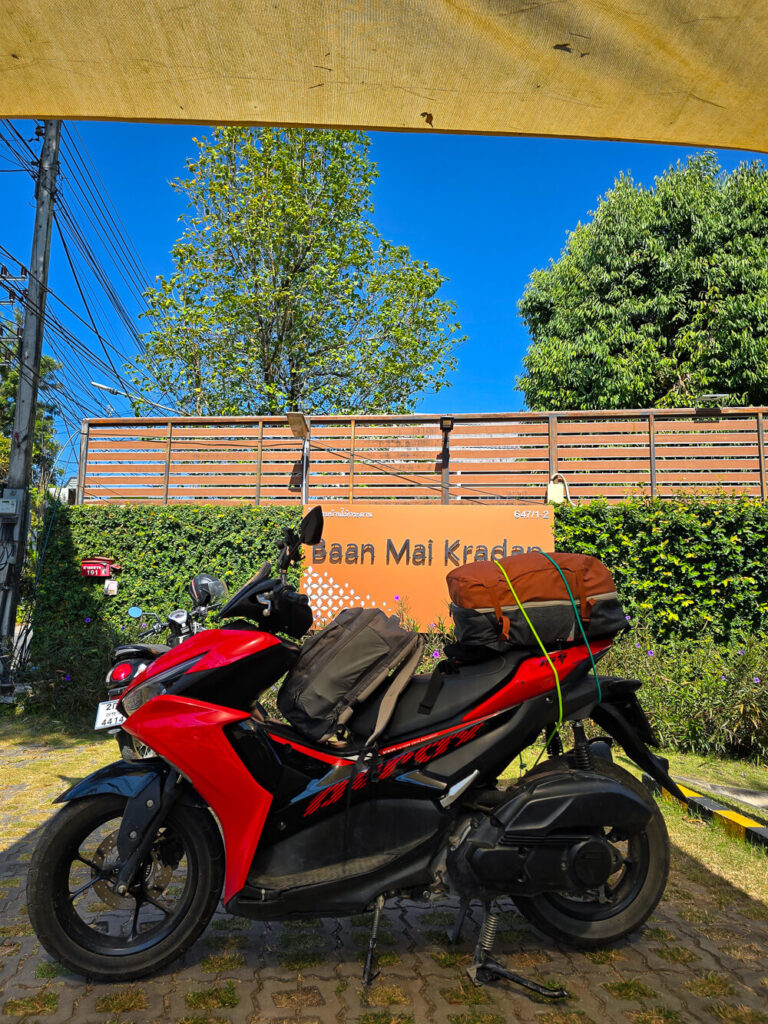A rental scooter packed with a rucksack and front backpack ready for a Northern Thailand budget travel road trip.
