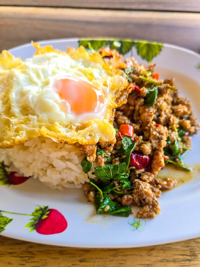 A plate of delicious local Pad Kra Pao street food, a staple for Northern Thailand budget travel.