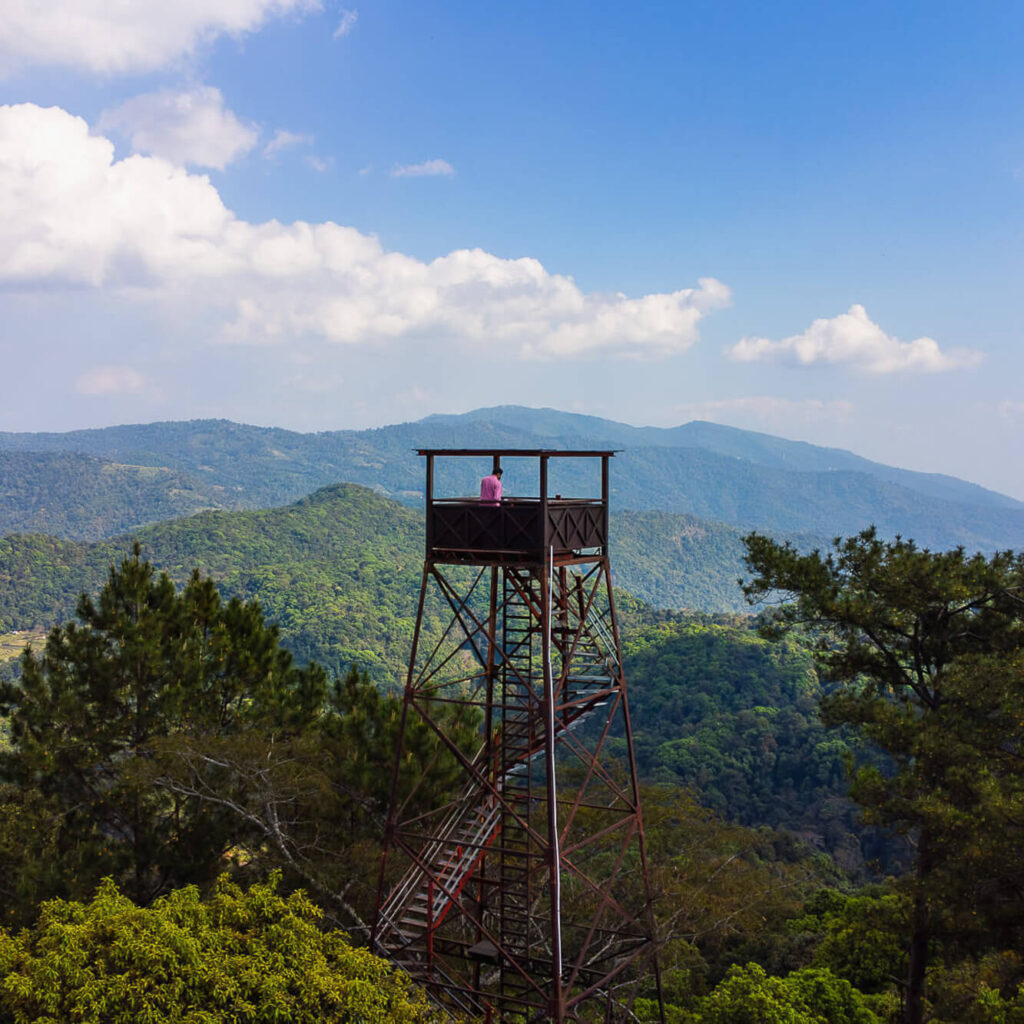 Cinematic drone shot of traveler at a watchtower on the Samoeng Loop near Chiang Mai.