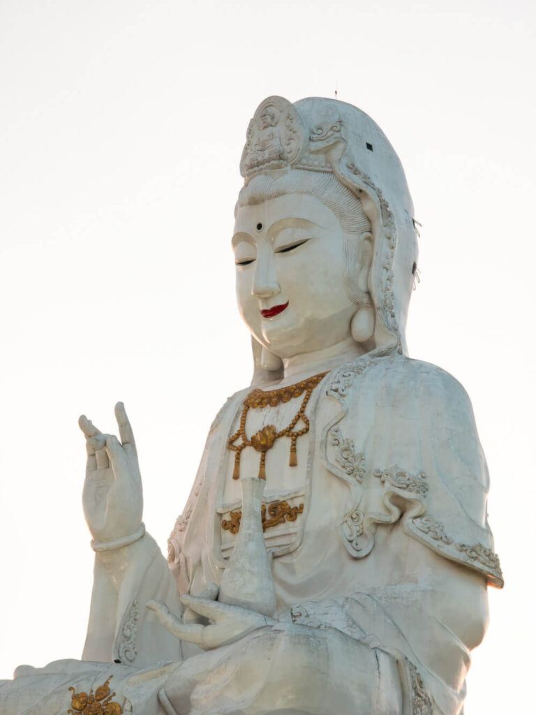 A close-up architectural shot showing the intricate facial details and massive scale of the white Guan Yin statue in northern Thailand.