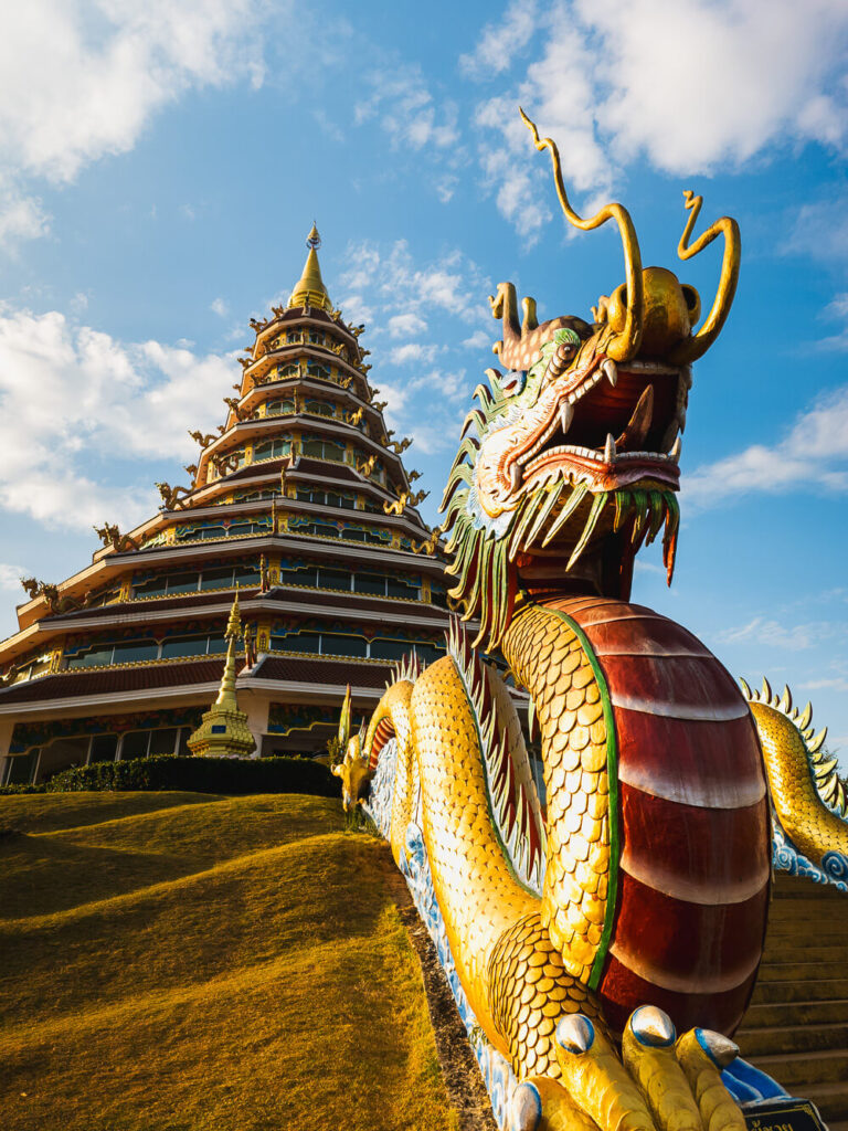 Detailed view of the colorful Chinese-style dragon head sculptures lining the staircase at the red pagoda in Chiang Rai.