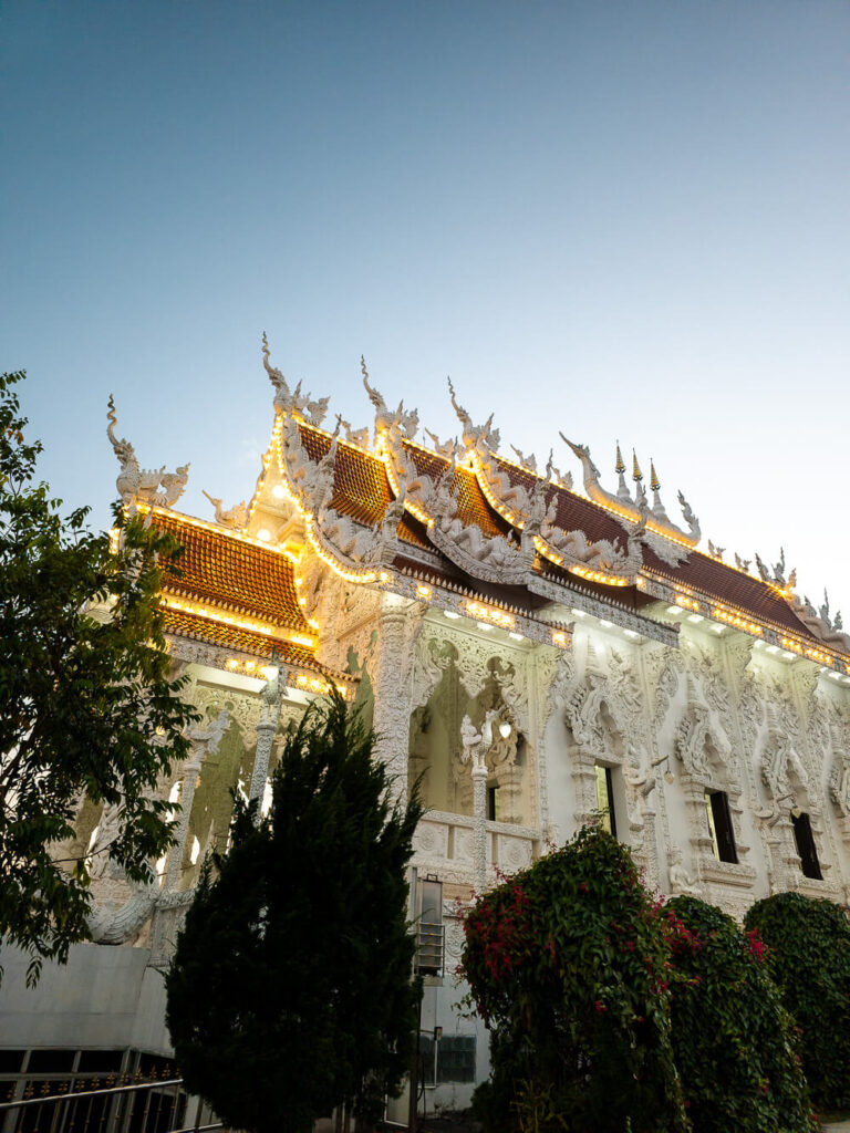 The peaceful and intricate gold interior of the traditional main temple hall at Wat Huay Pla Kang, featuring prayer areas and Buddha statues.