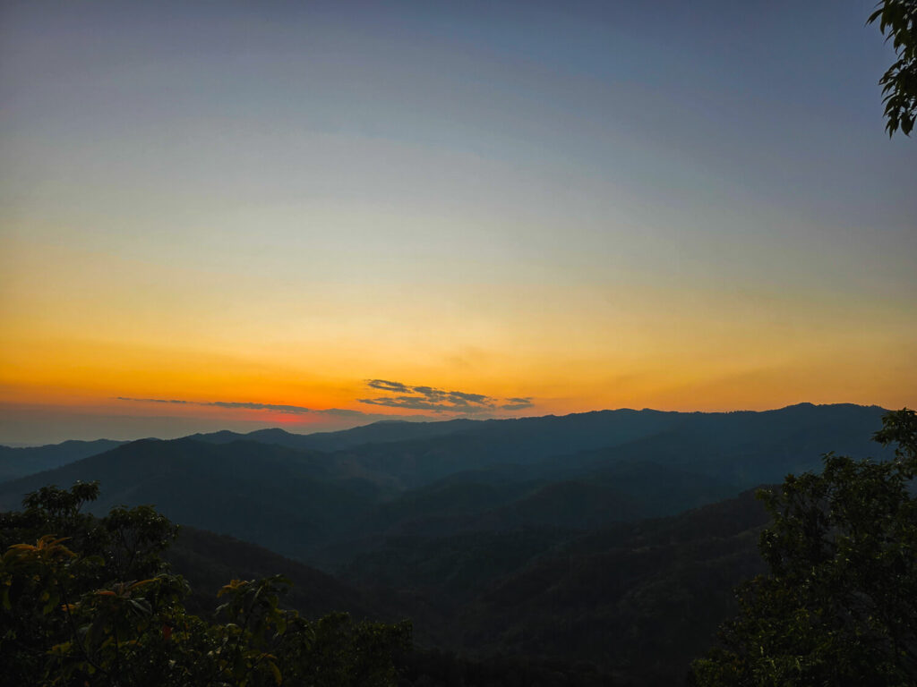 Golden hour sunset glowing over the mountains, valleys, and tea fields of Mae Salong.