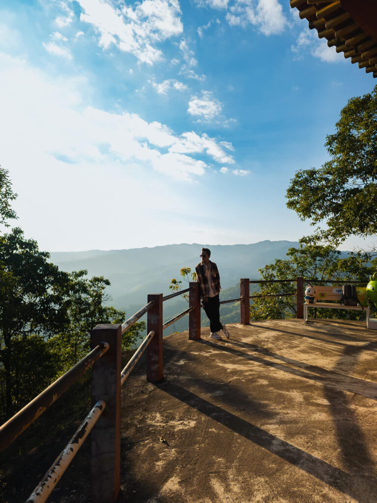 Traveler standing at the Mae Salong sunset viewpoint looking out over the layered mountain valleys.