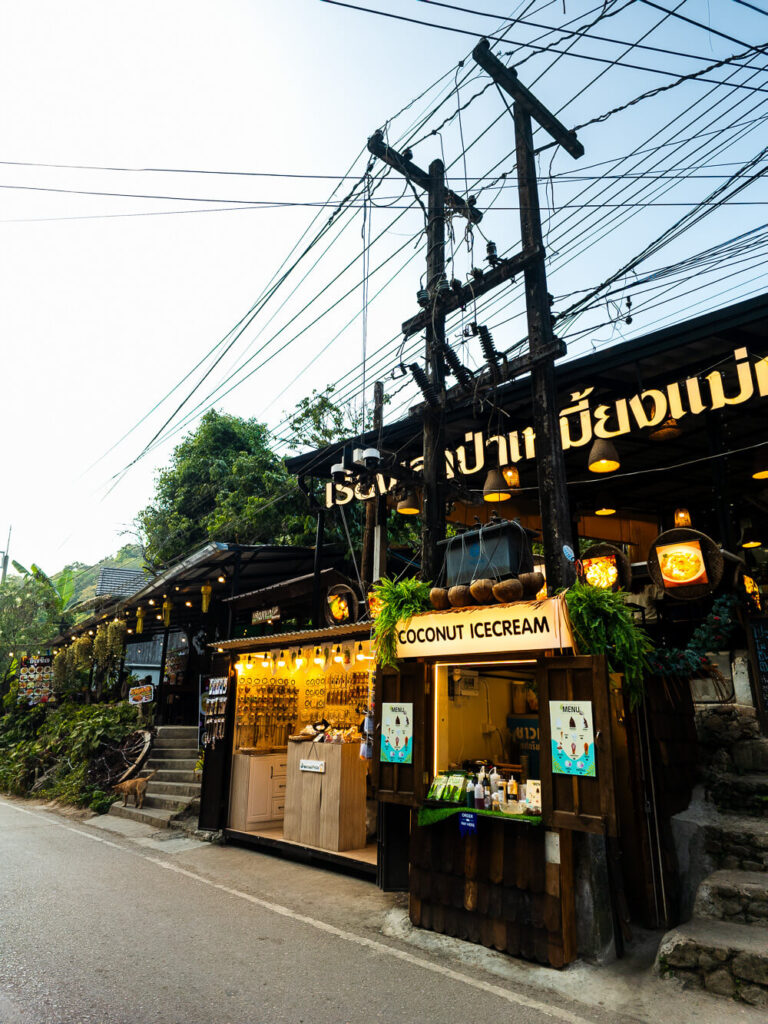 A rustic wooden café balcony in Mae Kampong overlooking the green valley and forest.