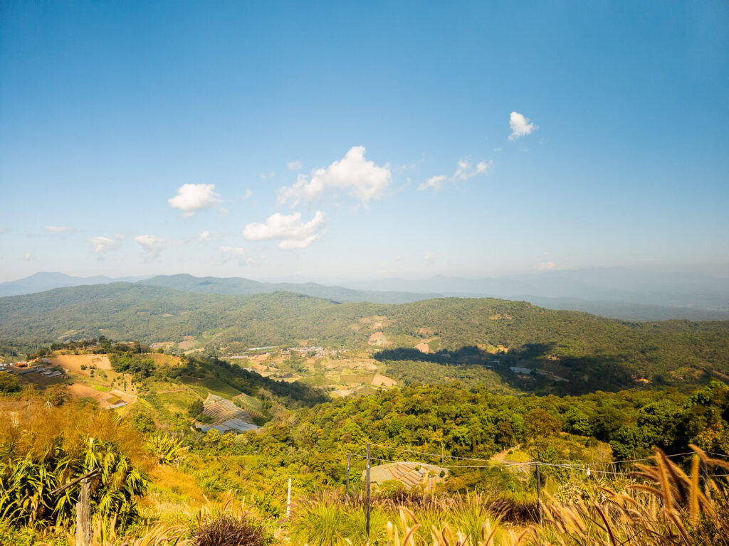 A scenic view of lush green mountains captured while riding a scooter in Northern Thailand toward Mae Kampong.