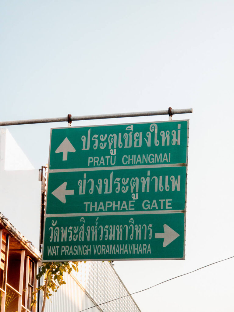 Street sign in Chiang Mai showing directions to local landmarks and temples.