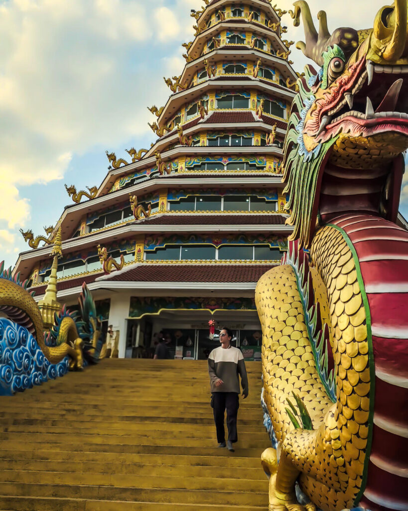 A traveler climbing the interior staircase of the red nine-tier pagoda at Wat Huay Pla Kang in northern Thailand.