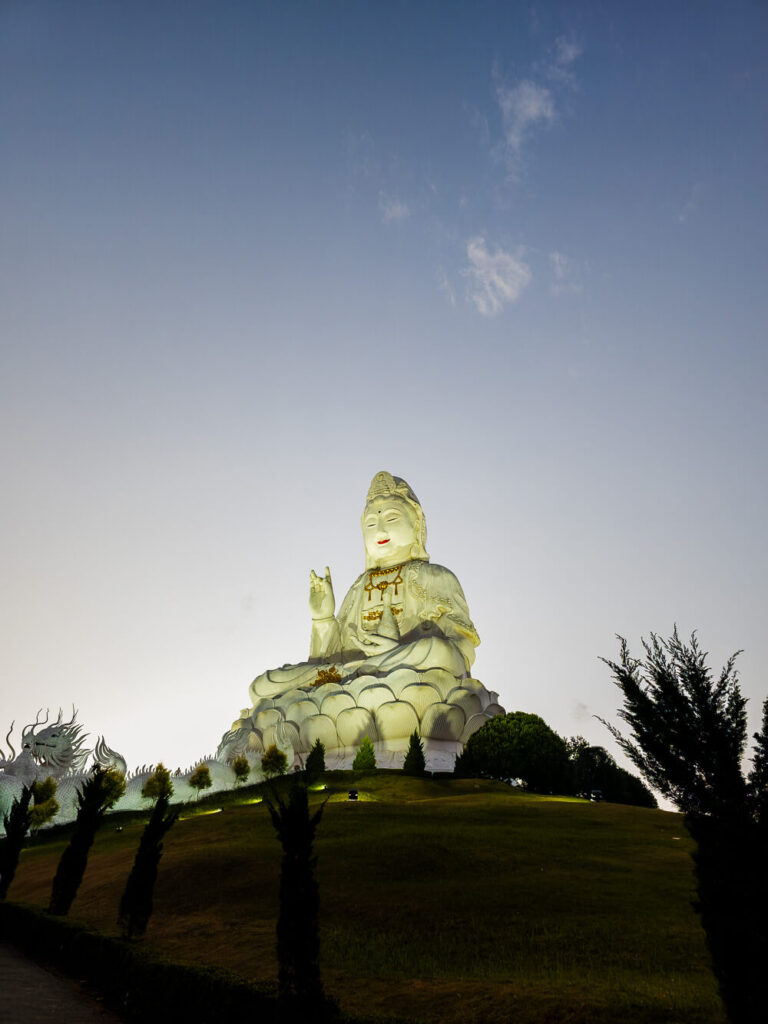 A sharp night photo of the illuminated Wat Huay Pla Kang statue in Chiang Rai captured on a smartphone.