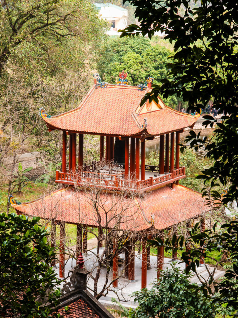 An ancient, traditional Vietnamese temple built against the towering limestone mountains in Ninh Binh.