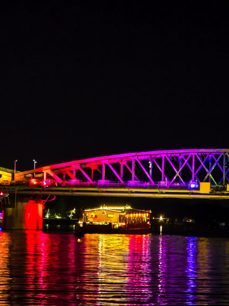 A vibrantly painted walking bridge spanning across a calm river in the historical city of Hue, Vietnam.