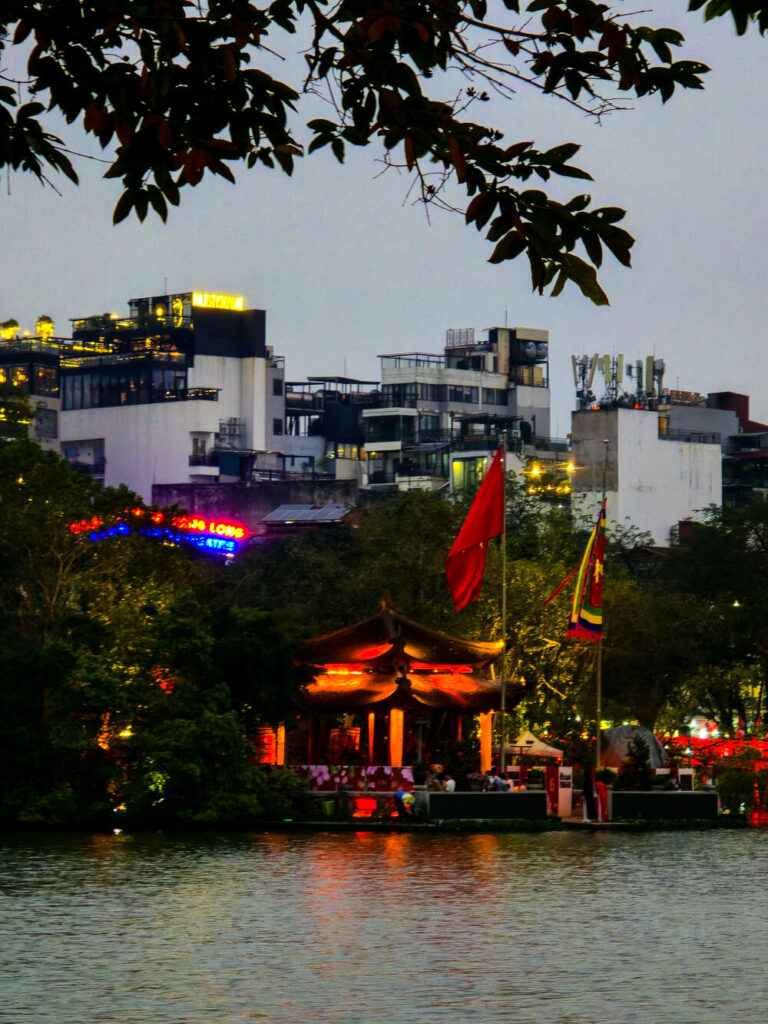 An evening view of Ngoc Son temple on Hoan Kiem Lake, beautifully illuminated against the night sky in Hanoi.