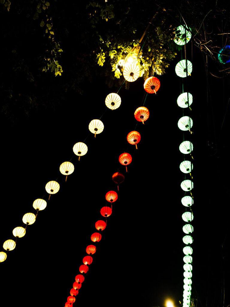 Colorful silk lanterns glowing brightly at night along the pedestrian-only streets of Hoi An Old Town.