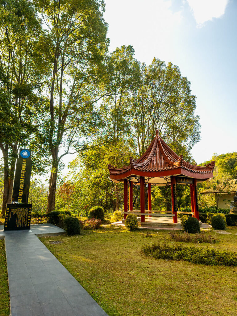 A massive old tree growing alongside a traditional Northern Thai temple structure with weathered stone and intricate details.