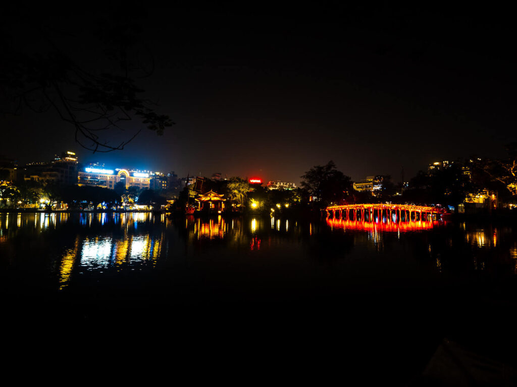 A night view of Ngoc Son Temple and the illuminated red Huc Bridge over Hoàn Kiếm Lake - Hanoi Travel Guide.