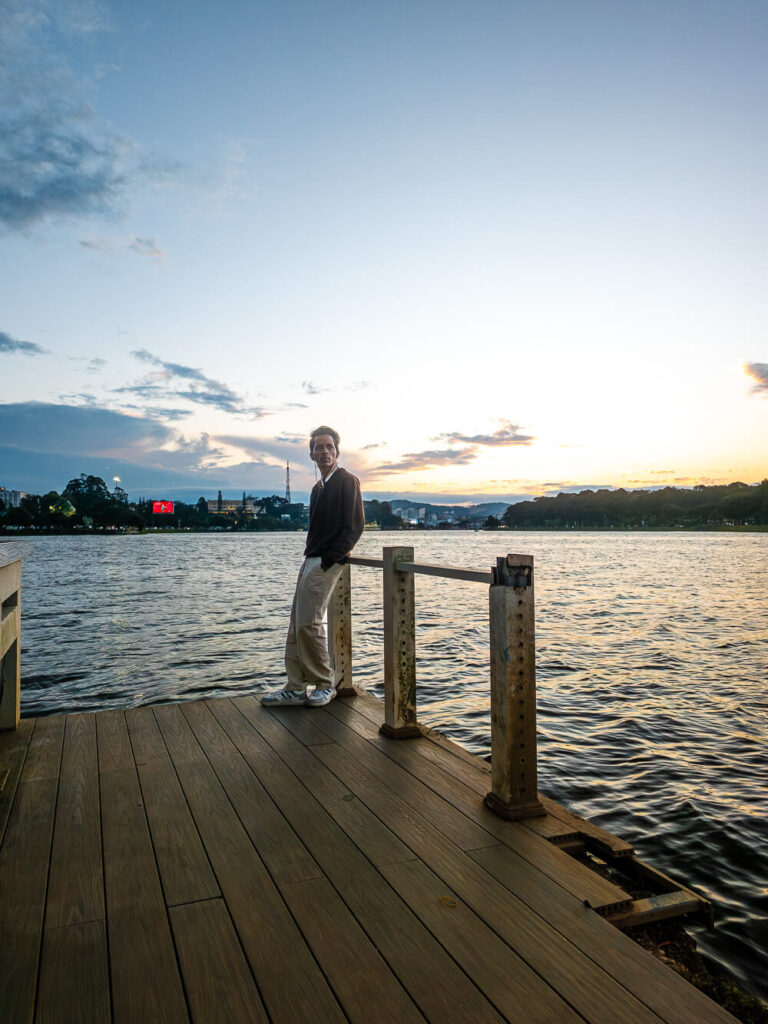 A traveler sitting by the edge of Xuan Huong Lake in Da Lat during a cool afternoon.