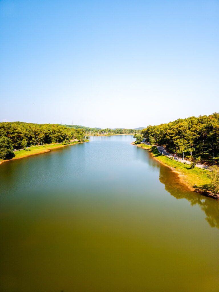 A wide landscape shot of the lush green banks along the Perfume River in Hue.
