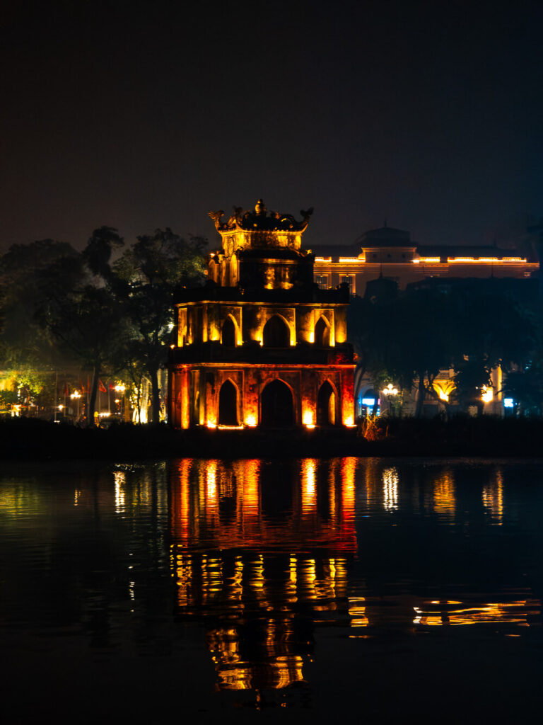 The historic Turtle Tower glowing at night in the center of Hoàn Kiếm Lake in Hanoi.
