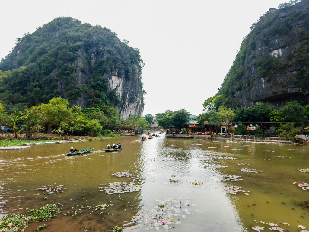 Traditional rowboats filled with people navigating the calm river waters amidst the limestone karsts at Trang An.