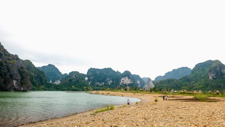 A scenic lakeside view of the limestone karst mountains in Trang An, the beautiful starting point for travelers getting from Ninh Binh to Hue.