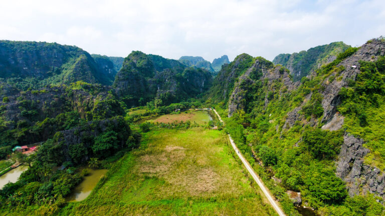 Aerial drone view of limestone karsts and the Ngo Dong river in Tam Coc, a key destination when planning how to travel from Hanoi to Ninh Binh.