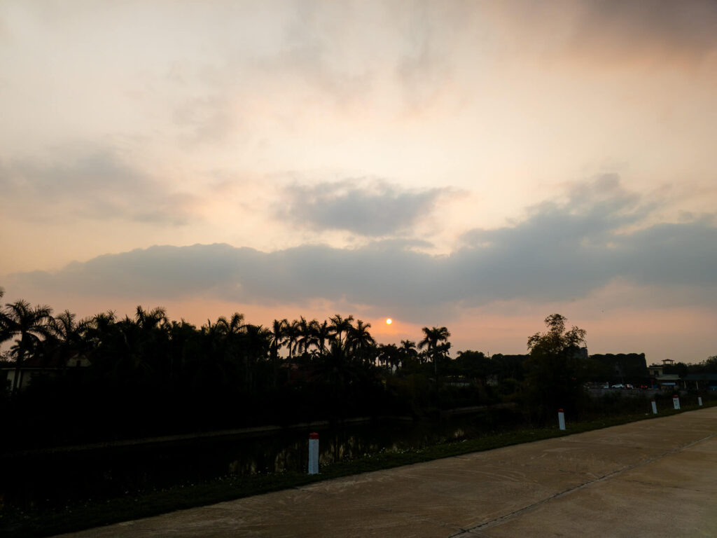 A golden sunset casting warm light over the towering limestone karsts and quiet rice fields of Ninh Binh.