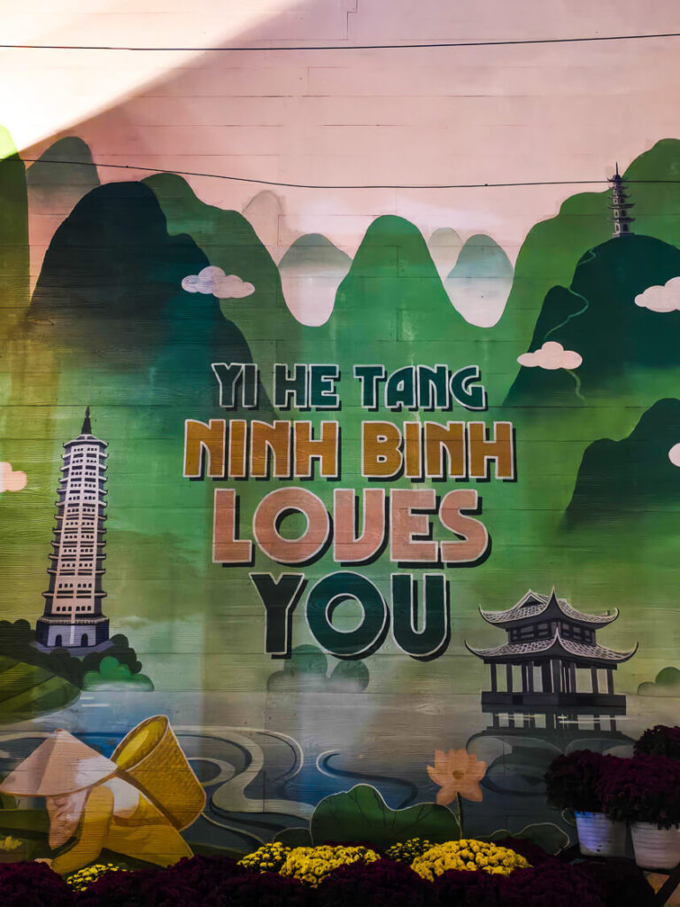 A brightly lit sign reading "Ninh Binh Loves You" glowing against the night sky in the city center