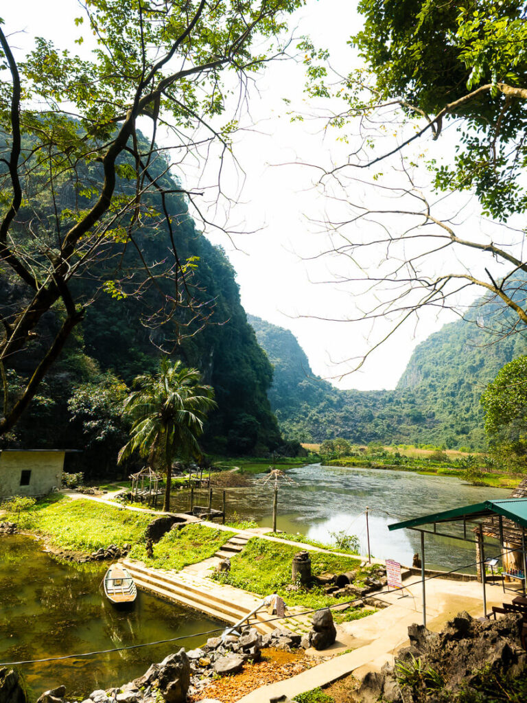 A wide scenic shot of the lily pad covered lake next to Bich Dong Pagoda.