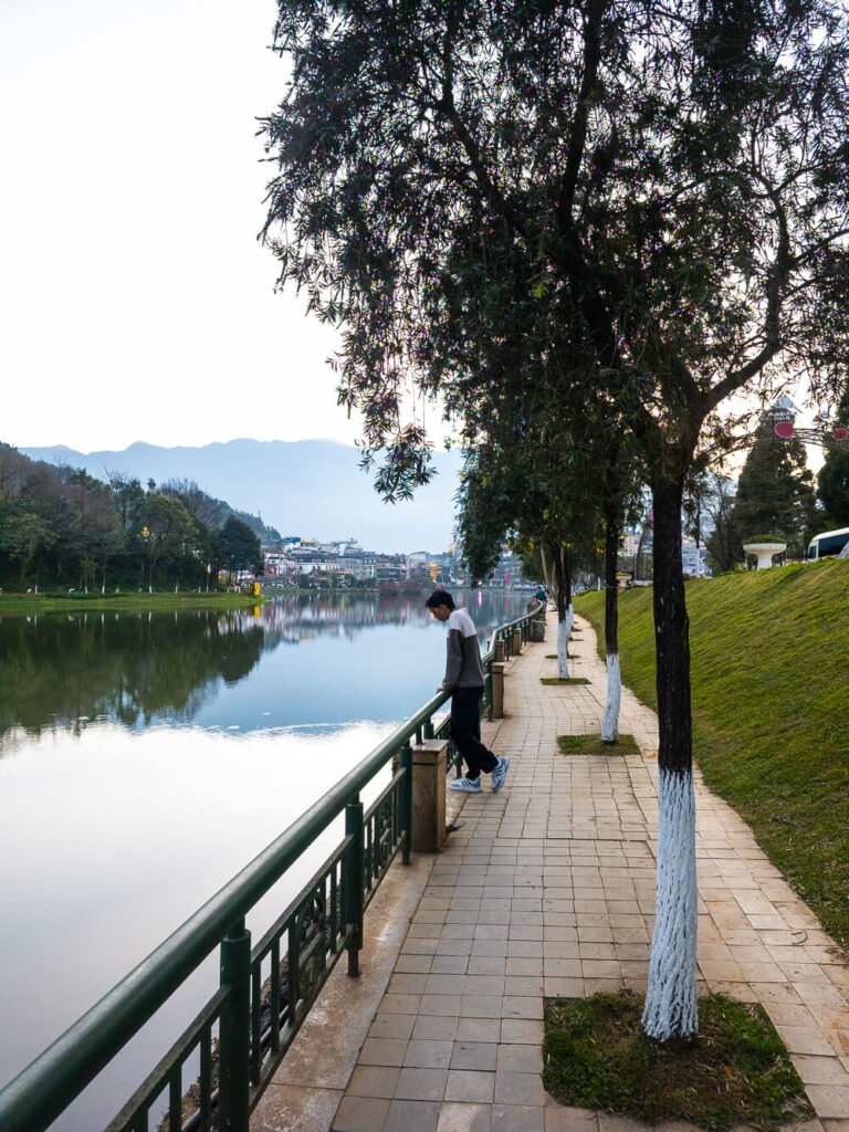 A traveler standing next to the peaceful waters of Sapa Lake during a trip to Northern Vietnam.