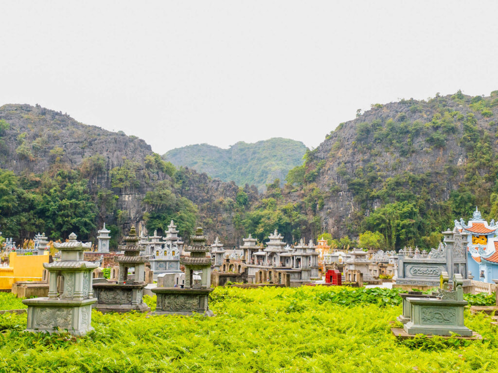 A quiet traditional cemetery resting amidst the rice paddies and limestone karsts along a rural road in Tam Coc.