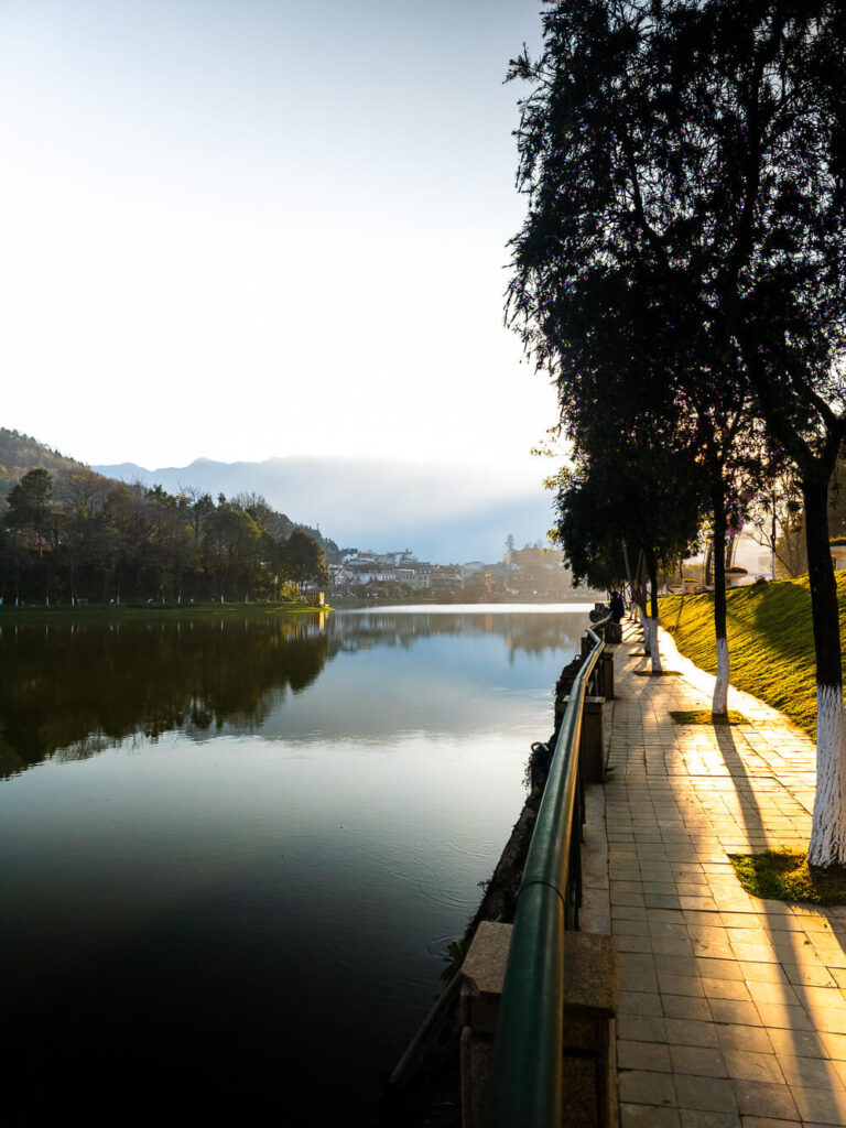 Calm water at sapa lake reflecting the colorful buildings and mountains under a clear sky