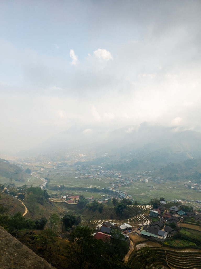 A wide landscape shot of Sapa trekking trails engulfed in thick white fog with low visibility.