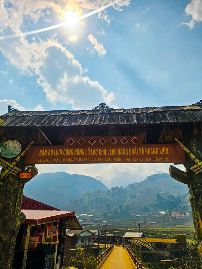 A wooden sign at the entrance of Lao Chai village in Sapa, marking the trekking route for independent travelers.