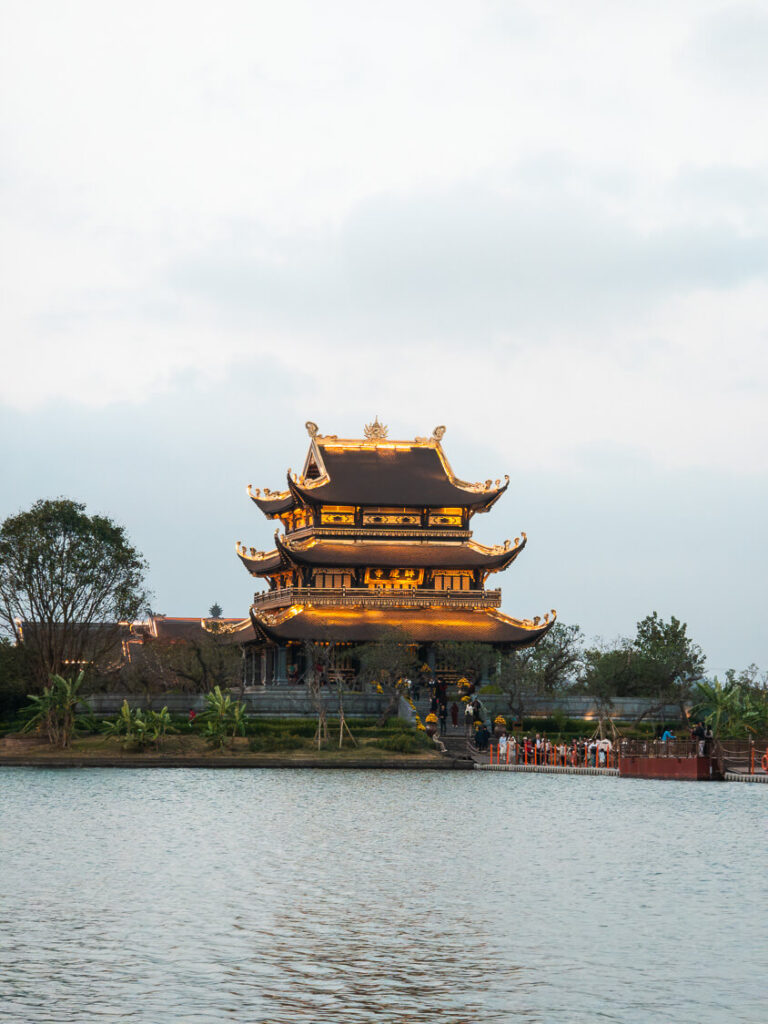 The golden Chua Vang pagoda structure resting on a small island surrounded by tranquil lake water in Ninh Binh
