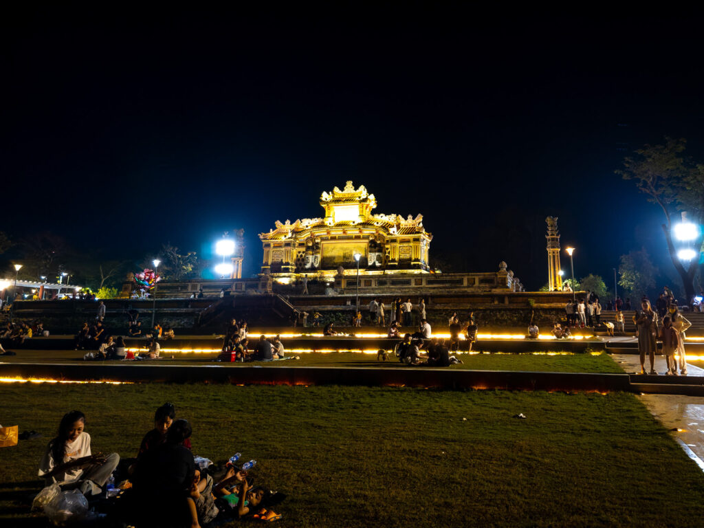 Nighttime view of the illuminated Dai Tuong Niem Chien memorial monument reflecting on the water along the Perfume River in Hue.