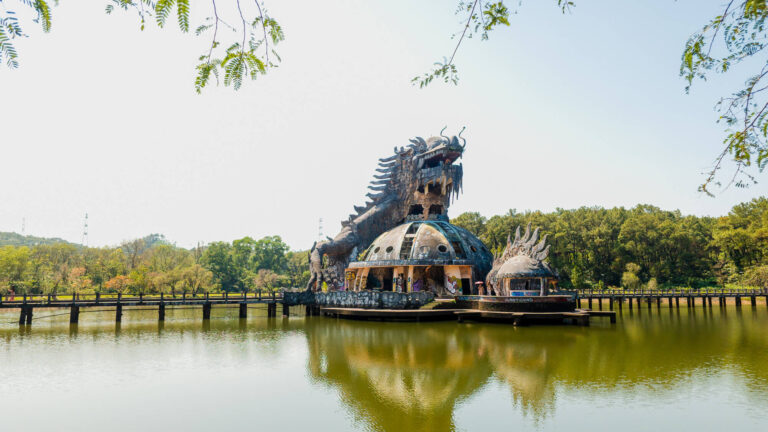 A wide landscape shot of the decaying three-story dragon structure at Ho Thuy Tien abandoned water park, one of the best hidden places in Hue.