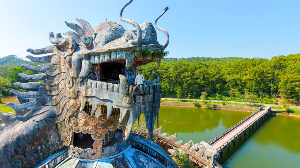 Front drone view of a person standing inside the giant concrete dragon head at Ho Thuy Tien