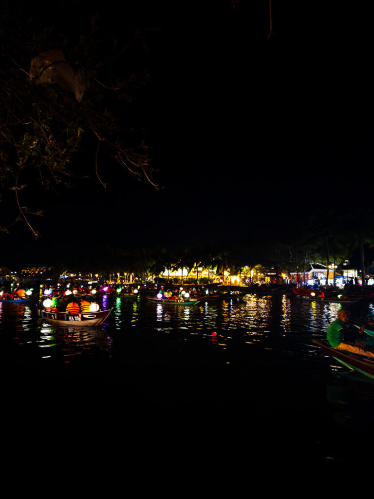 Illuminated colorful paper lanterns floating on the dark waters of the river in Hoi An at night.