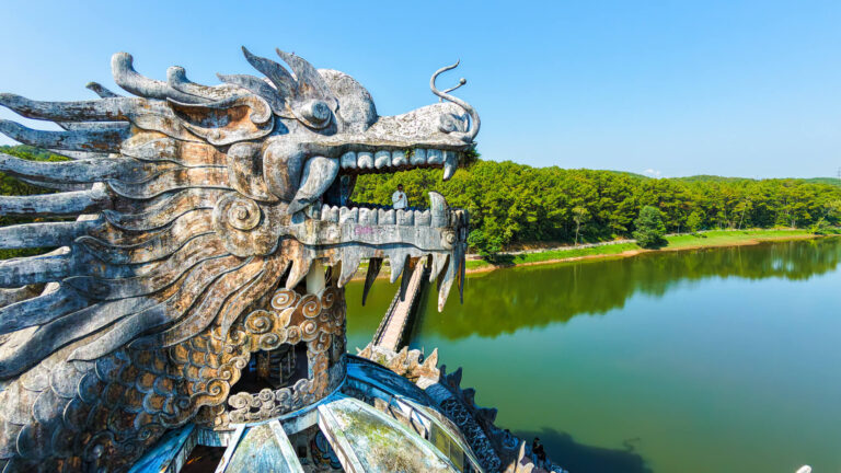 Aerial view of a traveler standing inside the mouth of the decaying dragon structure at the Hue Abandoned Water Park