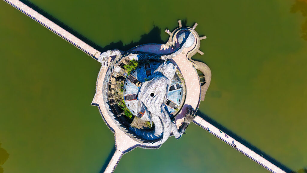 A top-down drone view looking directly at the circular concrete walkways and the massive head of the abandoned dragon at Ho Thuy Tien in Hue.