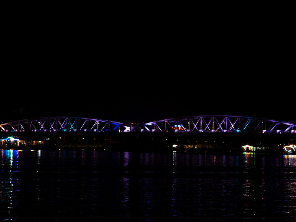 The illuminated Truong Tien Bridge crossing the Perfume River in Hue city center after dark.